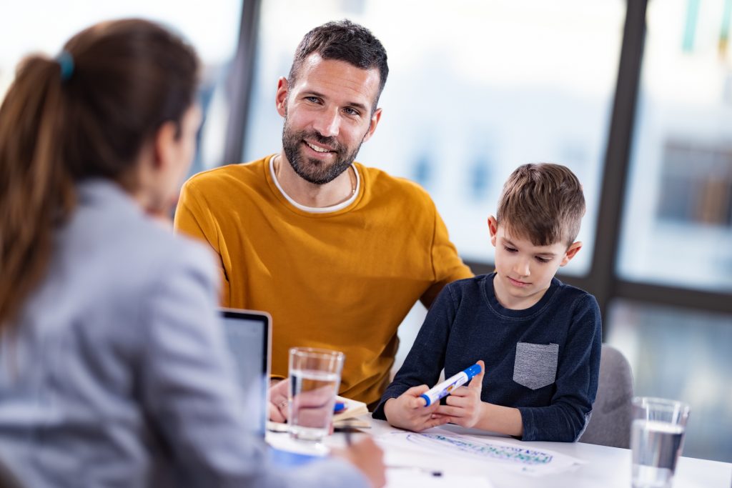 Happy father and his son having a meeting at school principal's office.